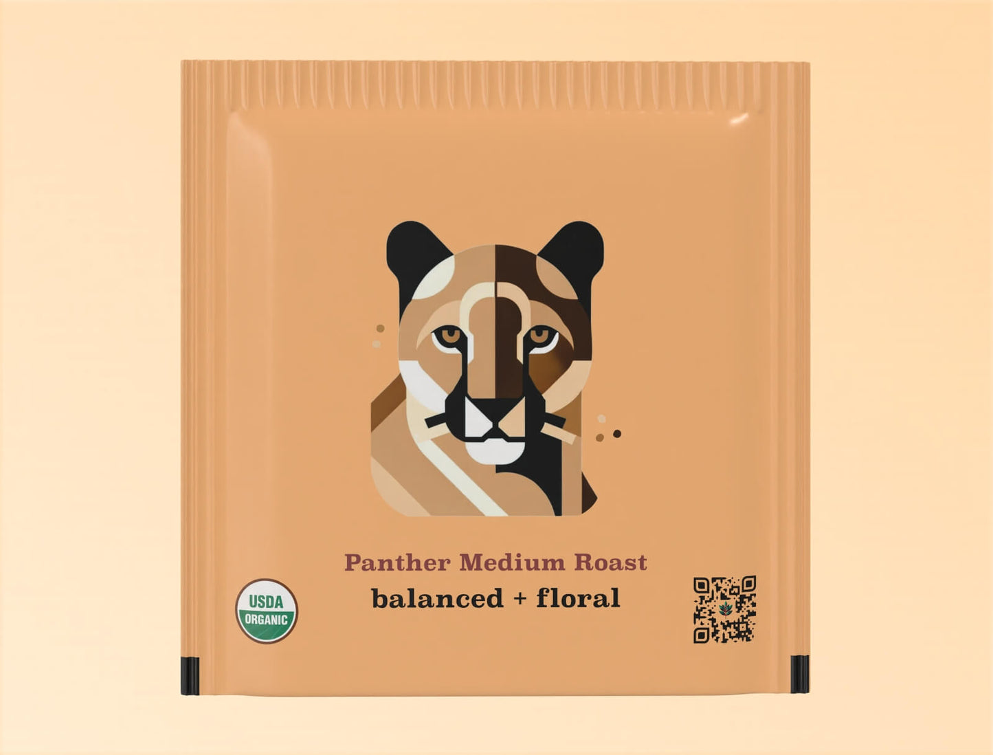 Individual teabag packaging for Goldholly's Panther Medium Roast yaupon tea. The tan-colored sachet features a geometric, color-blocked illustration of a panther face with distinctive markings in shades of brown, black, and cream. Below the illustration are the words 'Panther Medium Roast' and 'balanced + floral' in brown typography. The package includes a USDA Organic certification seal and QR code.