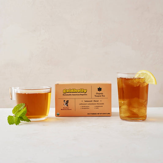 Goldholly Panther Medium Roast box with glass mugs of rich amber yaupon tea garnished with fresh mint and lemon. Balanced, floral notes shine through in this elegant product styling.