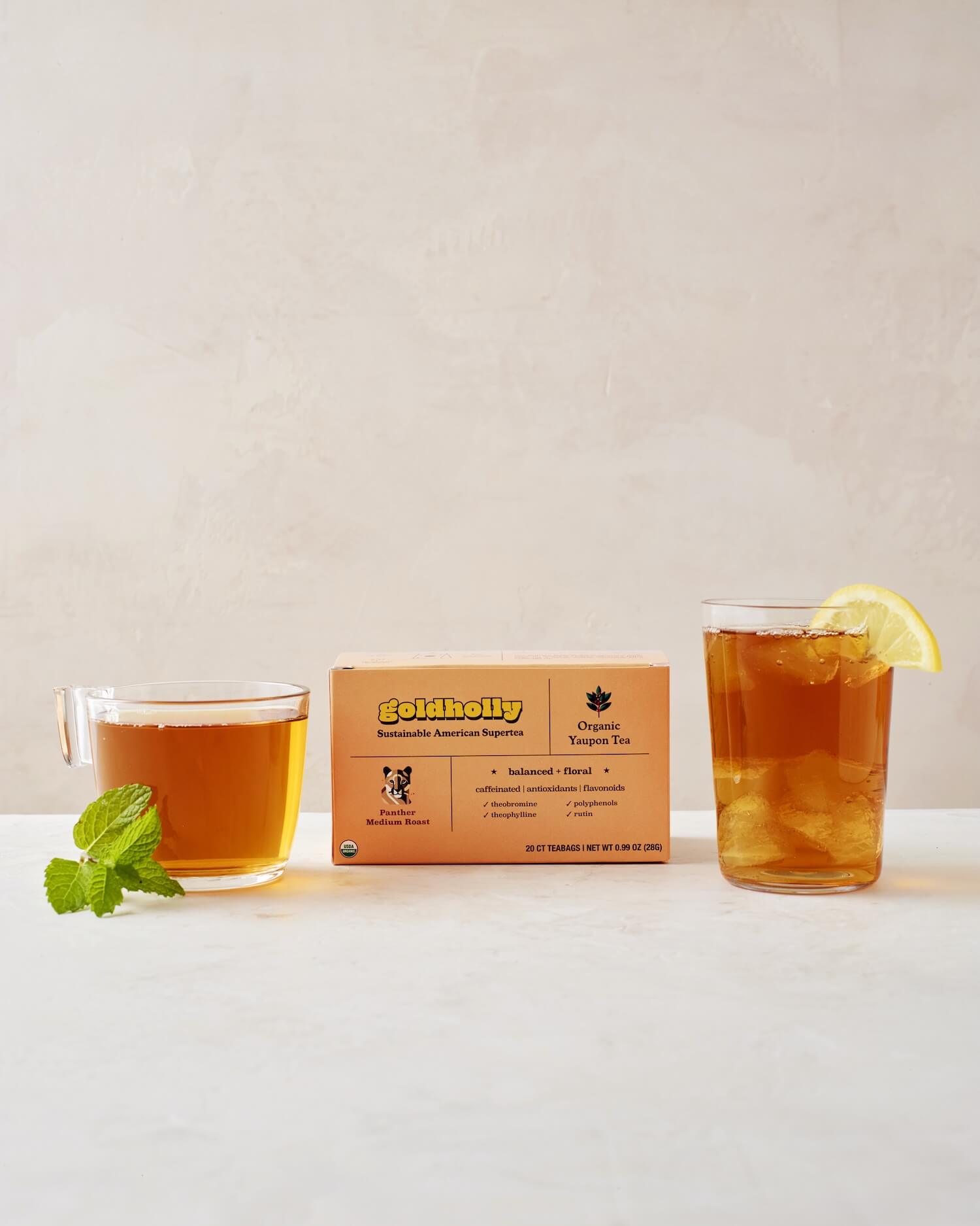 Goldholly Panther Medium Roast box with glass mugs of rich amber yaupon tea garnished with fresh mint and lemon. Balanced, floral notes shine through in this elegant product styling.