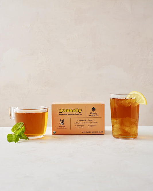 Goldholly Panther Medium Roast box with glass mugs of rich amber yaupon tea garnished with fresh mint and lemon. Balanced, floral notes shine through in this elegant product styling.