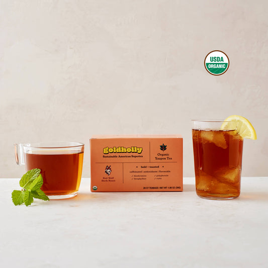 Goldholly Red Wolf Dark Roast box with glass mugs of deep amber yaupon tea garnished with fresh mint and lemon, with the USDA Certified Organic seal in the upper right side of the image. Bold, toasted flavor profile perfect for rich, satisfying caffeine experience.