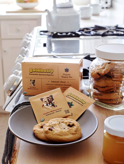 Bright kitchen counter with Goldholly Panther Medium Roast teabags and white ceramic mugs beside fresh-baked cookies. Natural morning light highlights the warm, inviting ritual of sustainable tea brewing.