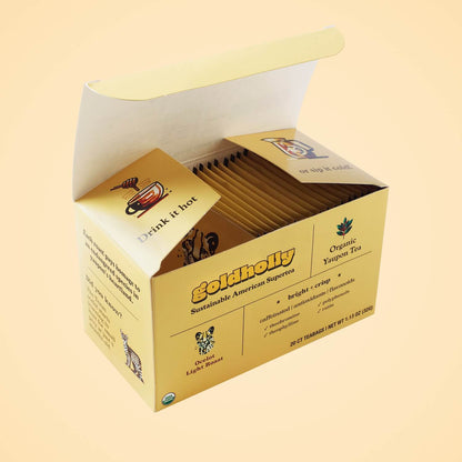 Opened Goldholly Ocelot Light Roast box revealing neatly arranged teabag packets with 'Drink it hot' message on interior flap, showcasing premium packaging design for organic yaupon tea.