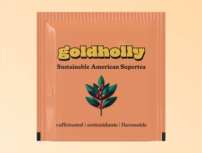Individual terracotta-colored teabag packaging for Goldholly yaupon tea. The sachet features the yellow Goldholly logo at top, 'Sustainable American Supertea' tagline, and a geometric illustration of a yaupon holly branch with green leaves and red berries. At the bottom is the text 'caffeinated | antioxidants | flavonoids' describing the tea's properties.