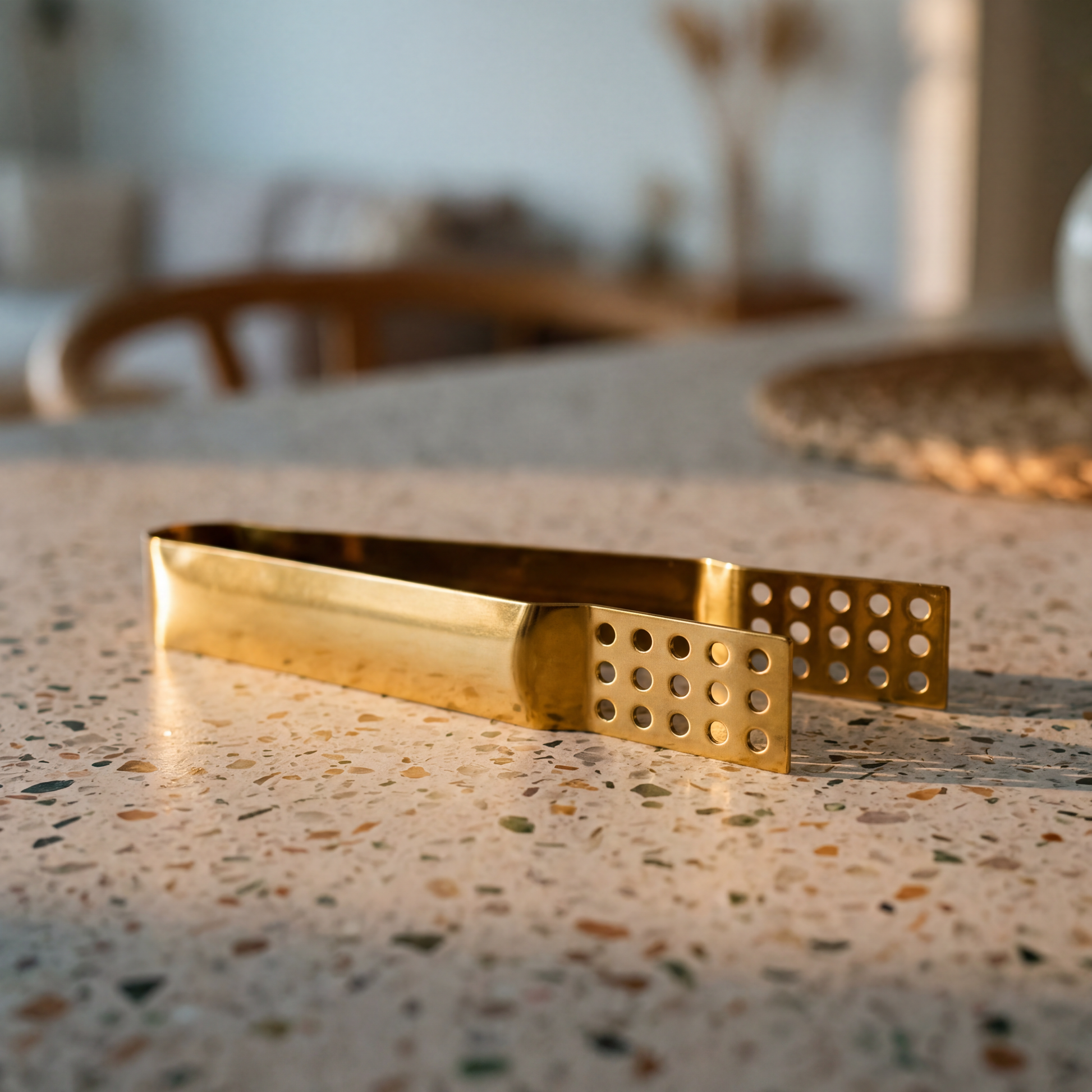 Gold teabag tongs on a granite counter.
