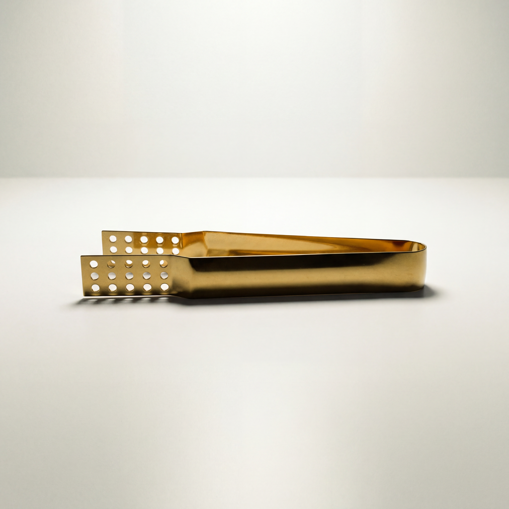 Closeup of golden metal teabag tongs on a white background.--8